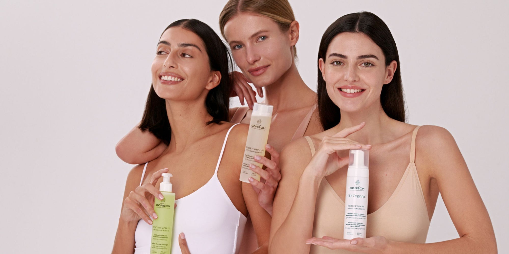 Tres mujeres con productos de skincare de FARMA DORSCH limpieza facial dermo cleanser gel, purifying Toner y micellar mousse en fondo neutro banner