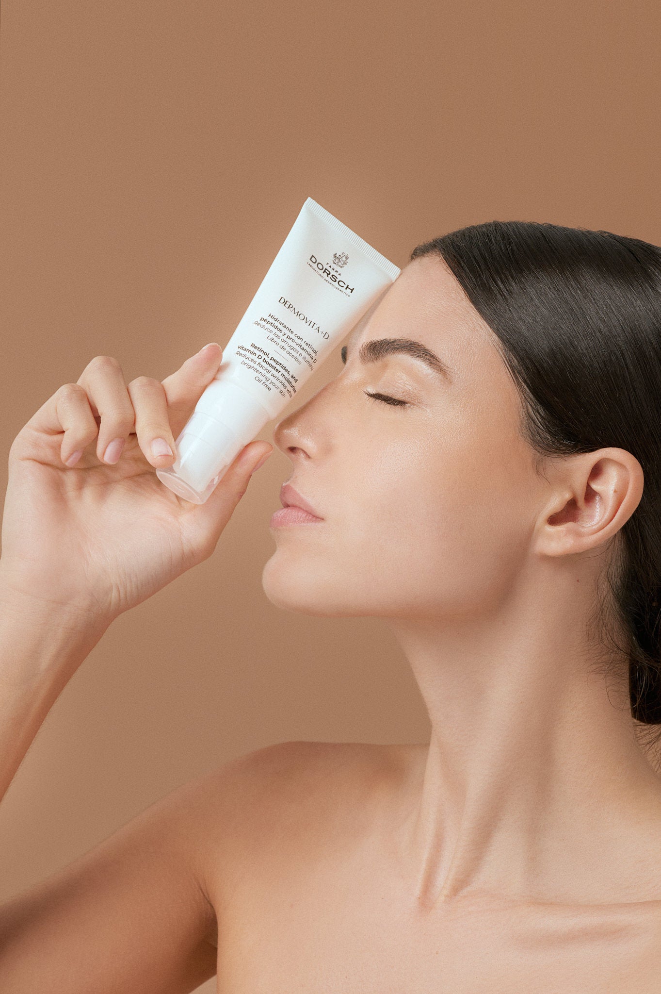 DERMOVITA + D, hidratante "oil free" ideal para pieles mixtas a grasas, combate las arrugas y mejora el tono de la piel sin obstruir los poros. Mujer con piel radiante sosteniendo el envase de Dermovita + D FARMA DORSCH, una crema hidratante antiedad que ilumina, reafirma y atenúa manchas, brindando una apariencia rejuvenecida.
