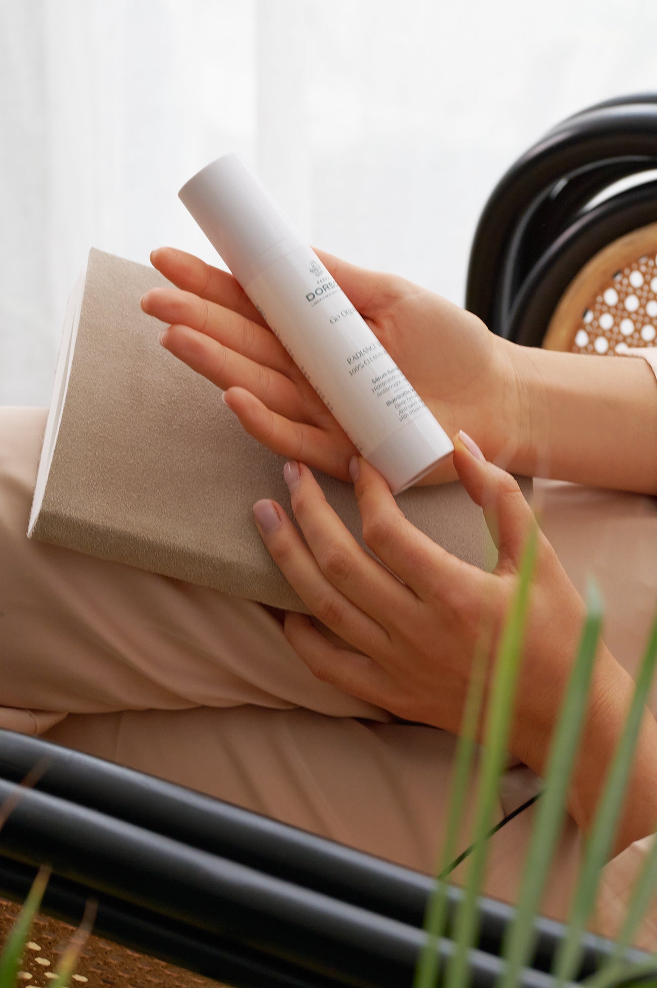 manos de mujer sosteniendo cilindro producto FARMADORSCH RADIANCE serum, mujer leyendo con pantalones beige