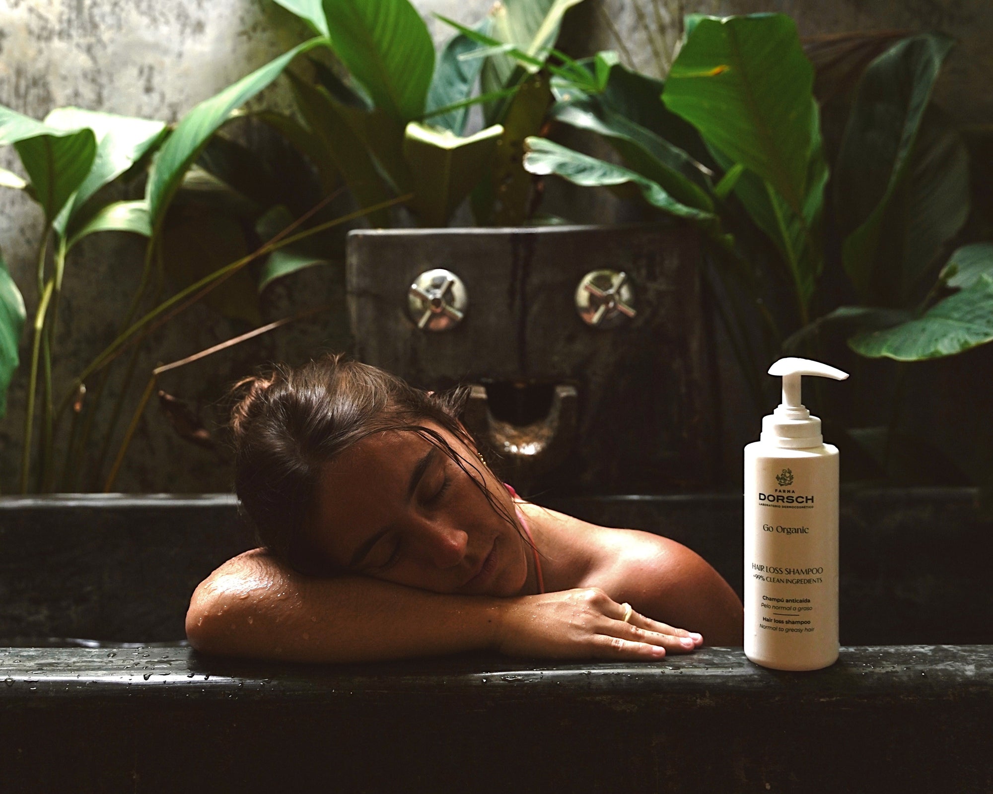 Mujer relajándose en una bañera tropical junto a Hair Loss Shampoo de FARMA DORSCH, tratamiento natural para prevenir la caída del cabello.