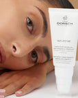 Mujer recostada junto a la crema Skin Repair de Farma Dorsch con vitamina F y rosa mosqueta, ideal para tratar arrugas, cicatrices y manchas.