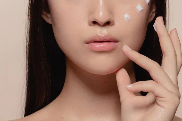 mujer coreana con tren gotas de crema sobre su cara