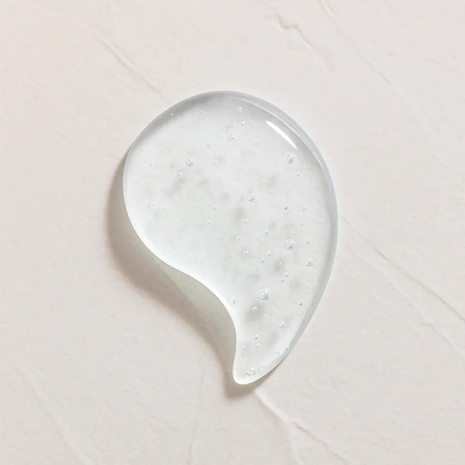 Gota transparente ligeramente amarillenta representando Ingrediente activo Acido Hialuronico Farma Dorsch para hidratacion profunda, relleno de arrugas y piel suave sobre fondo blanco texturizado en cosmetica natural española