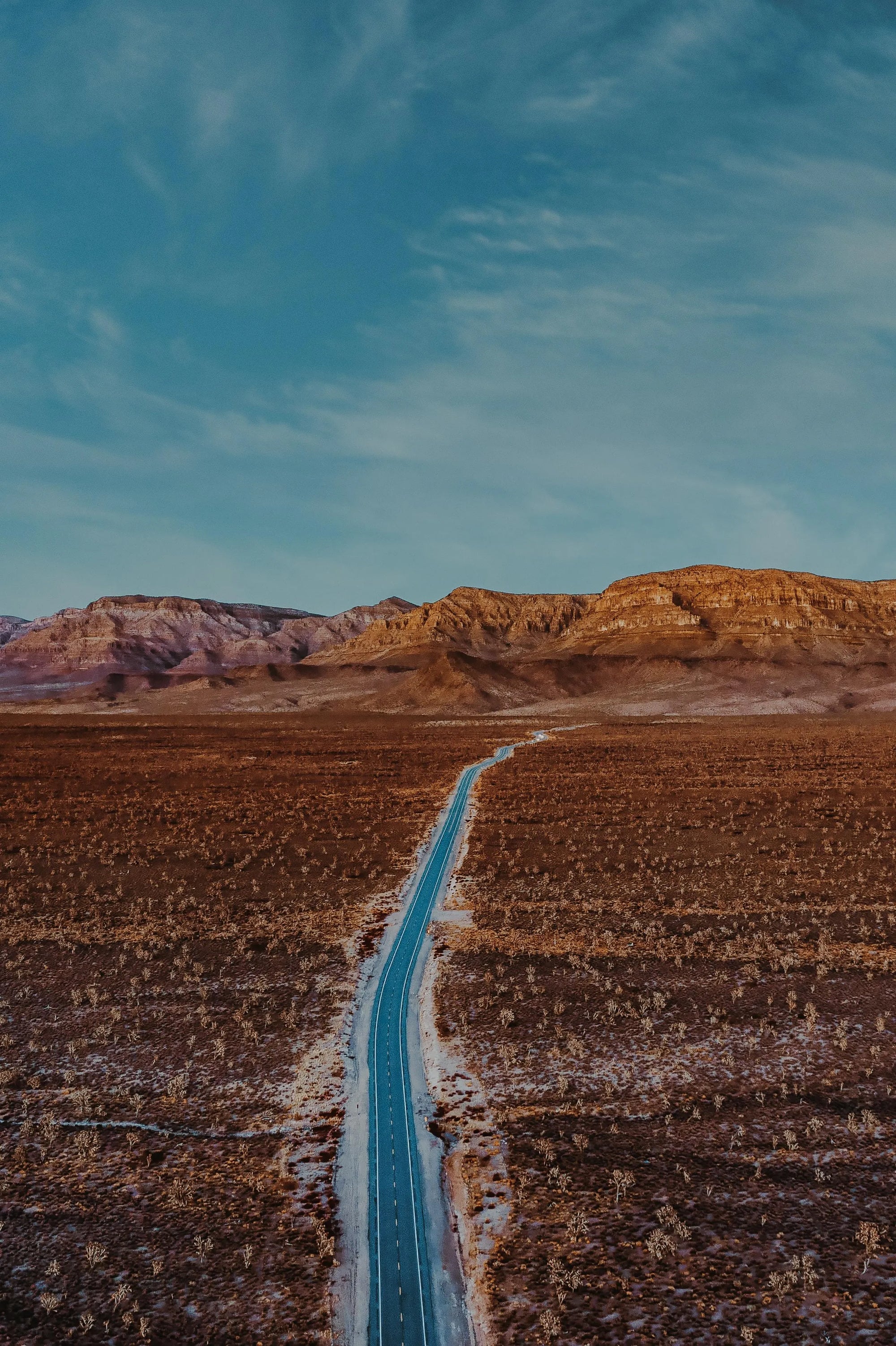 carretera recta atravesando paisaje desértico hacia montañas bajo cielo azul