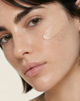 Mujer aplicándose la CC CREAM de FARMA DORSCH en la piel, crema hidratante con color, vitamina c y protección solar SPF50