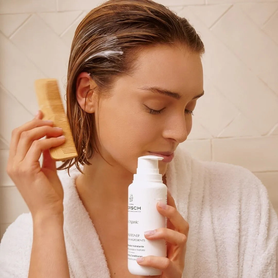 Mujer aplicando el acondicionador hidratante de FARMA DORSCH sobre el cabello húmedo.