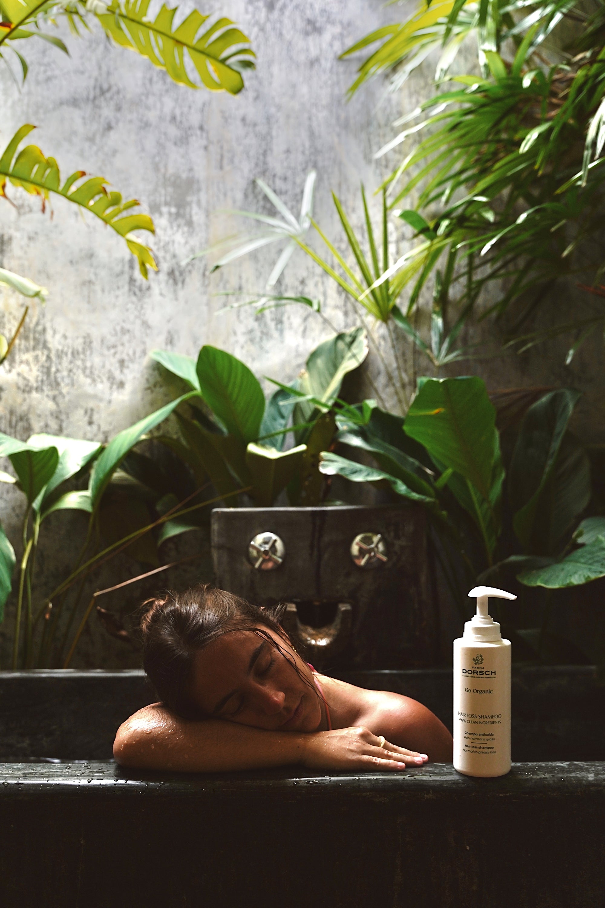 Mujer relajándose en una bañera tropical junto a Hair Loss Shampoo de FARMA DORSCH, tratamiento natural para prevenir la caída del cabello.