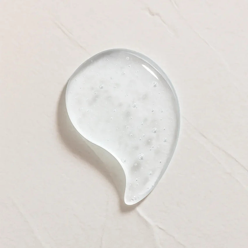 Gota transparente ligeramente amarillenta representando Ingrediente activo Acido Hialurónico Farma Dorsch para hidratación profunda, relleno de arrugas y piel suave sobre fondo blanco texturizado en cosmética natural española