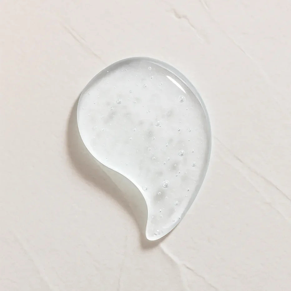 Gota transparente ligeramente amarillenta representando Ingrediente activo Acido Hialurónico Farma Dorsch para hidratación profunda, relleno de arrugas y piel suave sobre fondo blanco texturizado en cosmética natural española