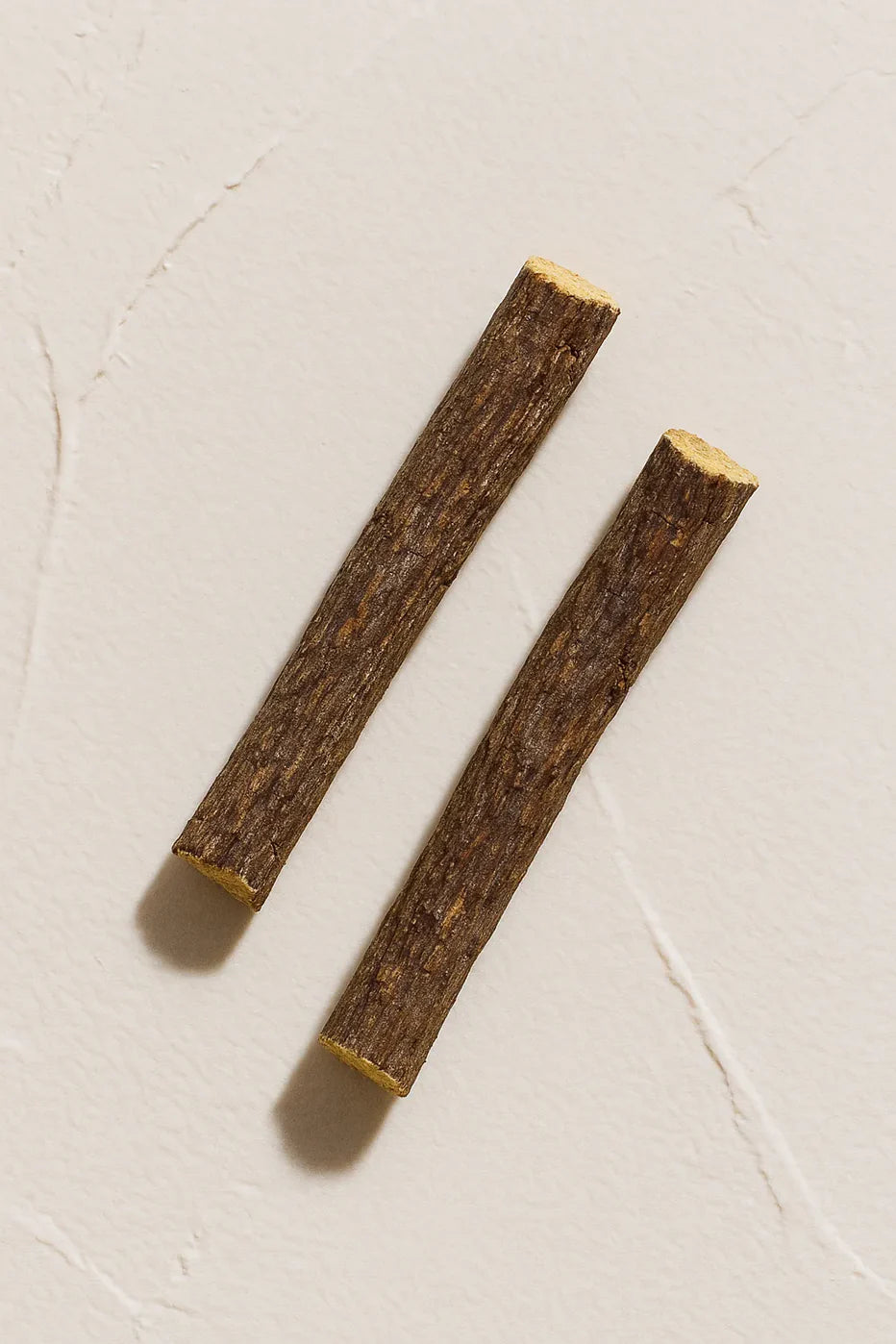 Dos trozos de raíz de regaliz extracto de raíz Ingrediente activo Regaliz Farma Dorsch con propiedades calmantes, antiinflamatorias y antioxidantes para piel sensible sobre fondo blanco suave en cosmética natural española