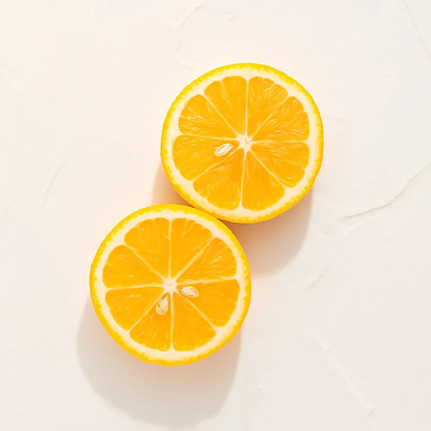 Dos rodajas de naranja representando Ingrediente activo Vitamina C Farma Dorsch con potente acción antioxidante, iluminadora y protectora para tratamiento facial y corporal sobre fondo blanco suave en cosmética natural española