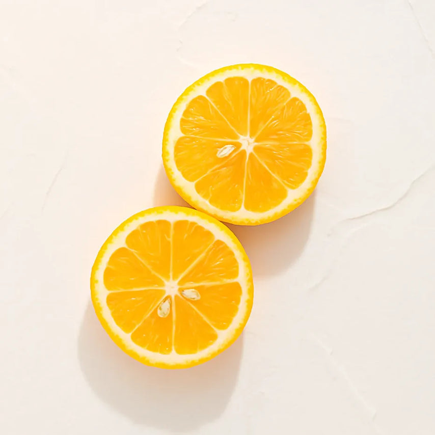 Dos rodajas de naranja representando Ingrediente activo Vitamina C Farma Dorsch con potente acción antioxidante, iluminadora y protectora para tratamiento facial y corporal sobre fondo blanco suave en cosmética natural española