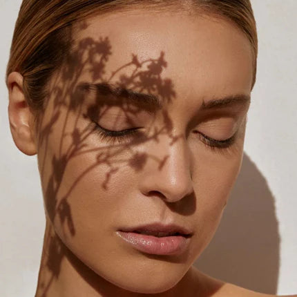 Mujer en luz natural directa con sombra de flores proyectada en rostro FARMA DORSCH ORAL SUN PROTECTION