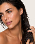 Mujer aplicando ANTIFRIZZ SERUM de FARMA DORSCH para conseguir un cabello más suave, hidratado y manejable.