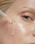 Mujer aplicando GOLD DROPS de FARMA DORSCH en el rostro para nutrir, iluminar y mejorar la elasticidad de la piel.