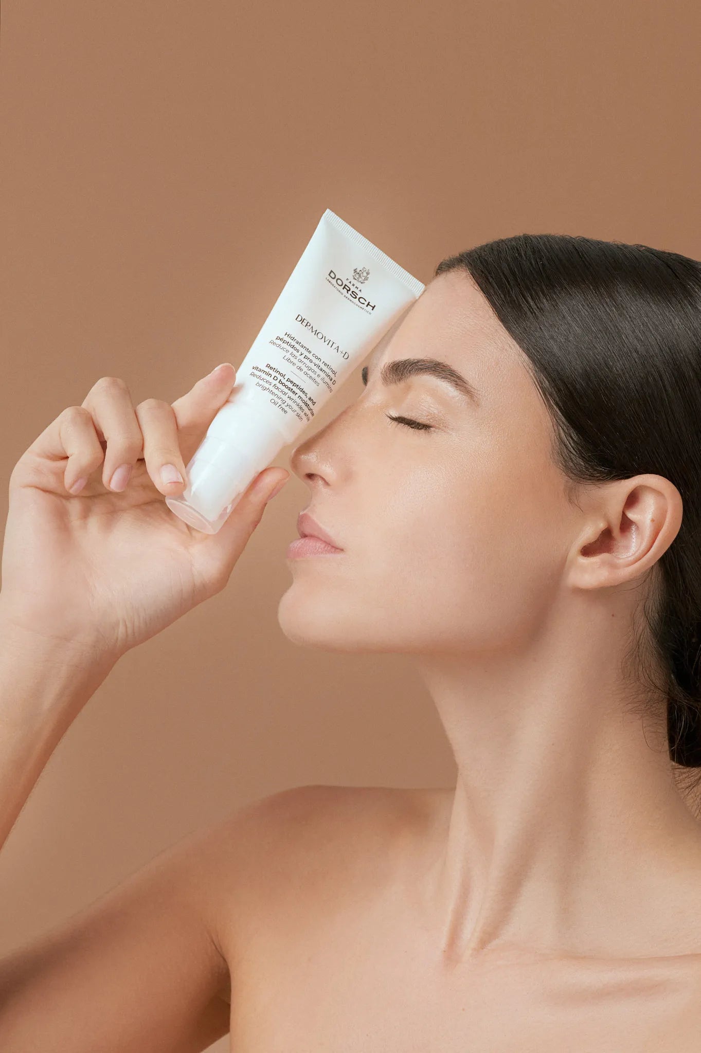 mujer sosteniendo producto facial FARMA DORSCH junto a la cara destacando la DERMOVITA + D