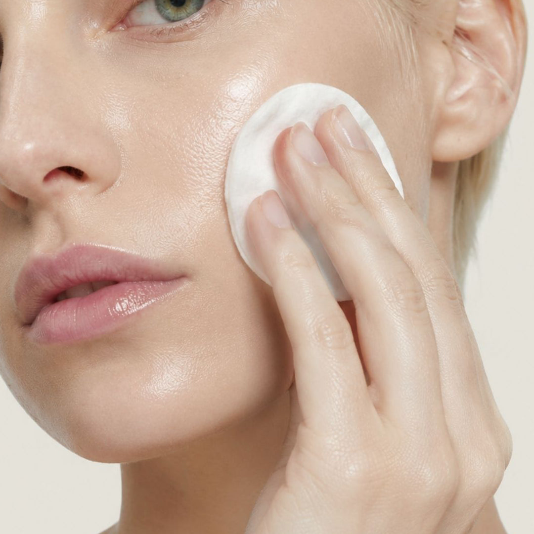 Mujer aplicando PURIFYING TONER de FARMA DORSCH en el rostro para equilibrar la piel y mejorar el aspecto de los poros.