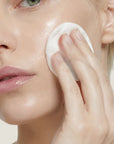 Mujer aplicando PURIFYING TONER de FARMA DORSCH en el rostro para equilibrar la piel y mejorar el aspecto de los poros.
