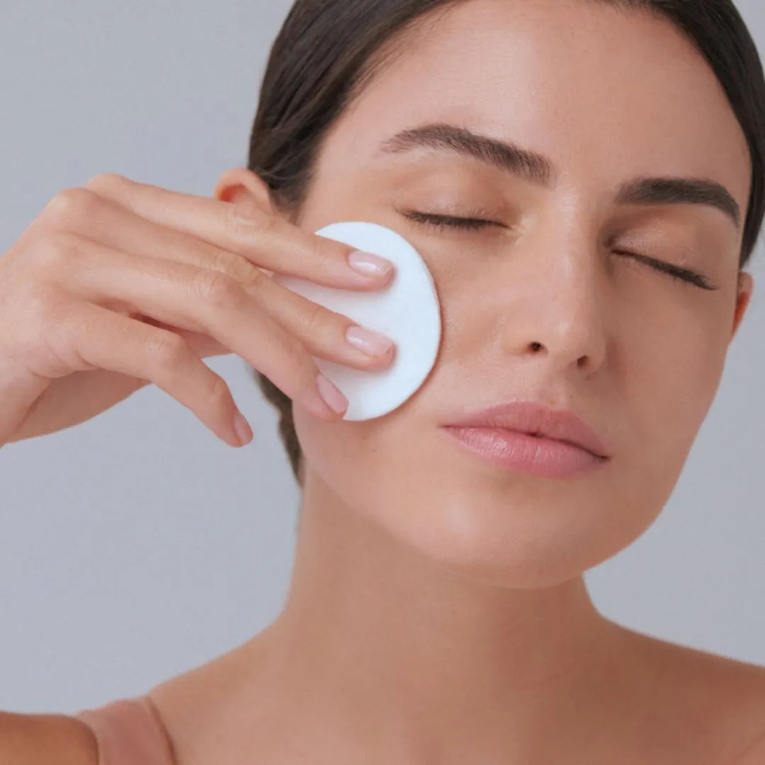 mujer aplicando tónico FARMA DORSCH con algodón sobre el rostro para limpiar y equilibrar la piel