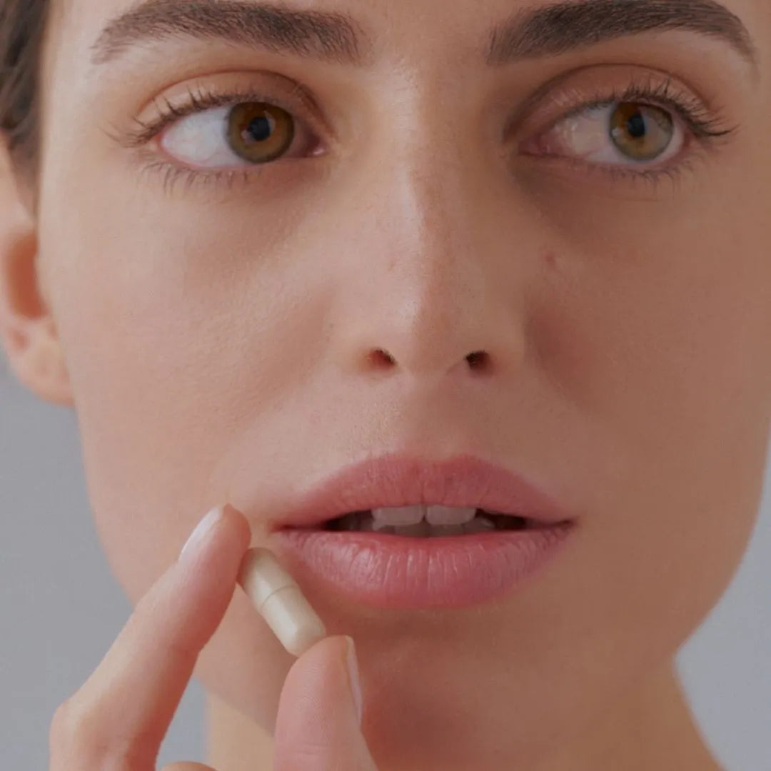 Primer plano de una mujer a punto de tomar un complemento alimenticio en cápsula, asociado a VISION BAGS & CIRCLES de FARMA DORSCH, formulado para combatir bolsas y ojeras desde el interior. Suplemento nutricosmético con ingredientes activos de alta eficacia.